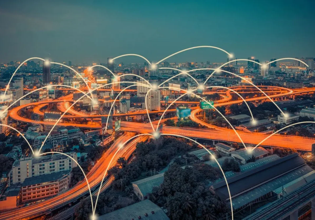 View of urban area with lit up highways intertwining superimposed with multiple lit up data point and connecting curved lines