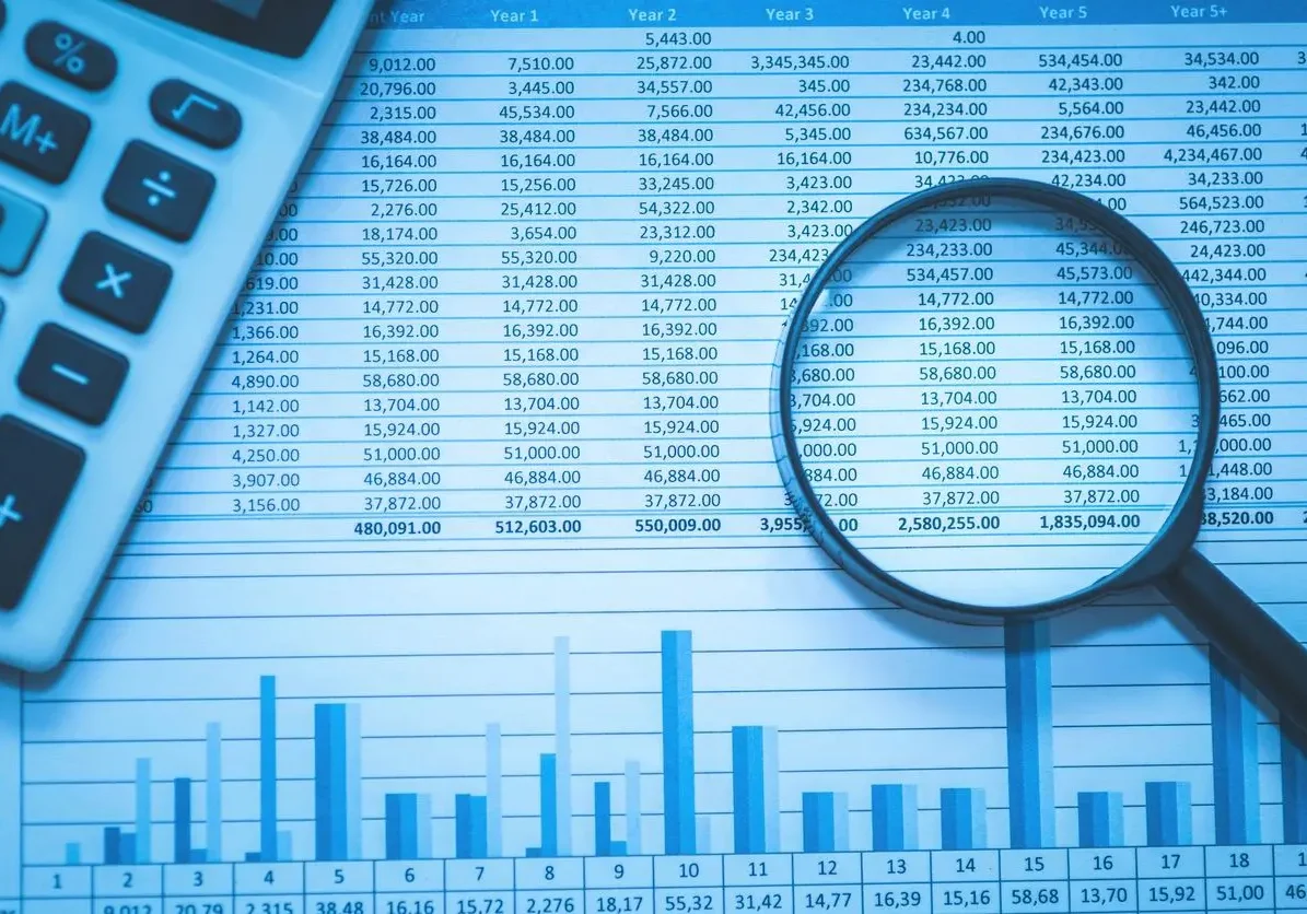 Close up of graphs and numbers with magnifying glass reviewing capital planning numbers