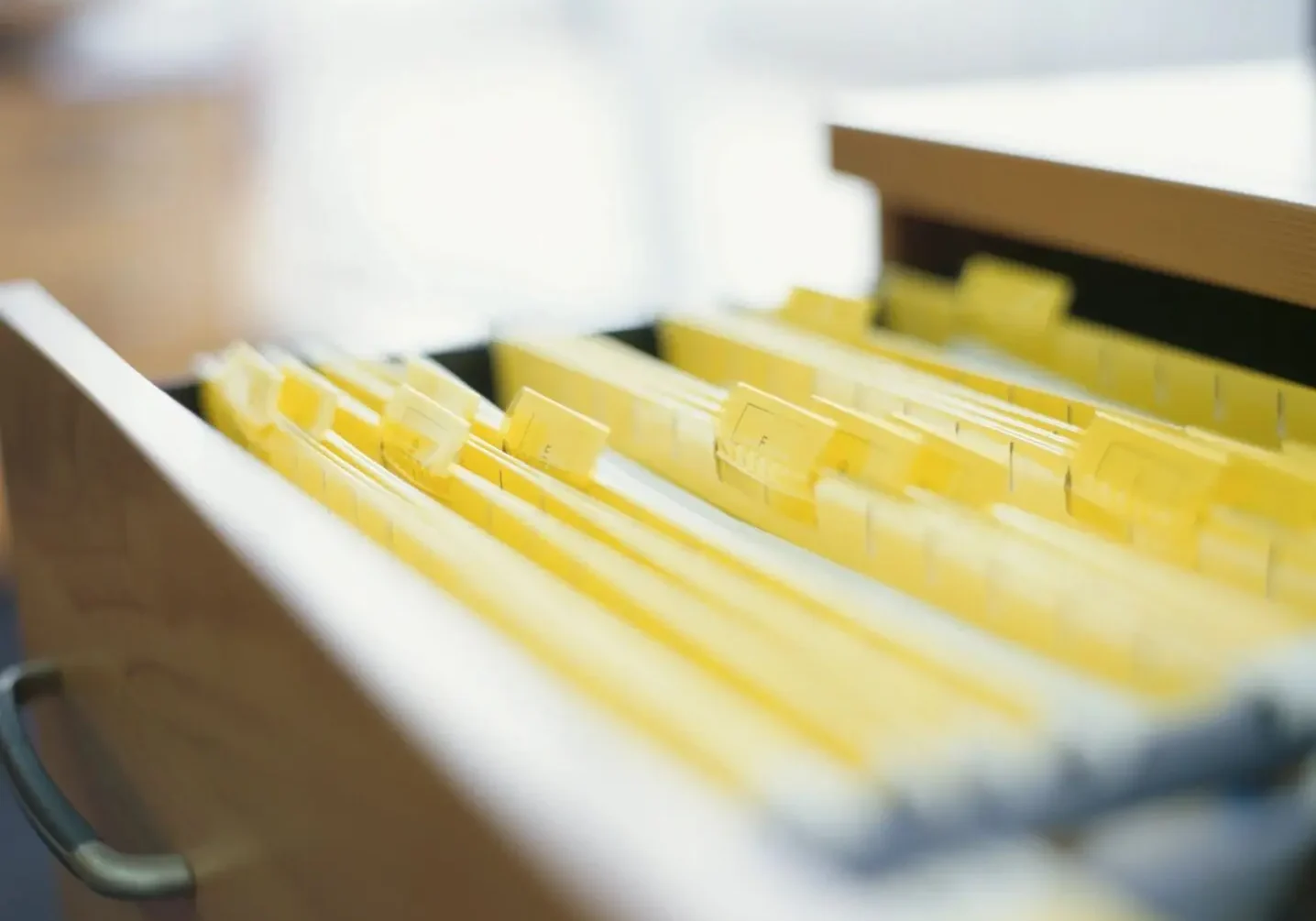 Extreme Close up of filing cabinet drawer full of yellow tabbed files and paperwork