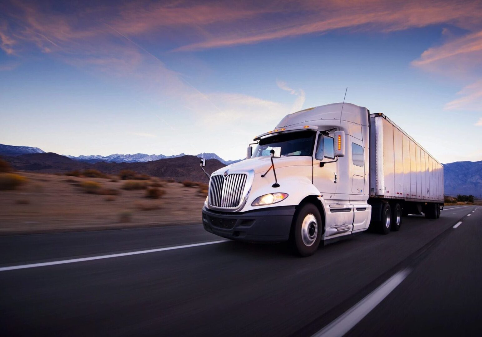 18-wheeler truck driving down a highway to represent transportation and industrial sector